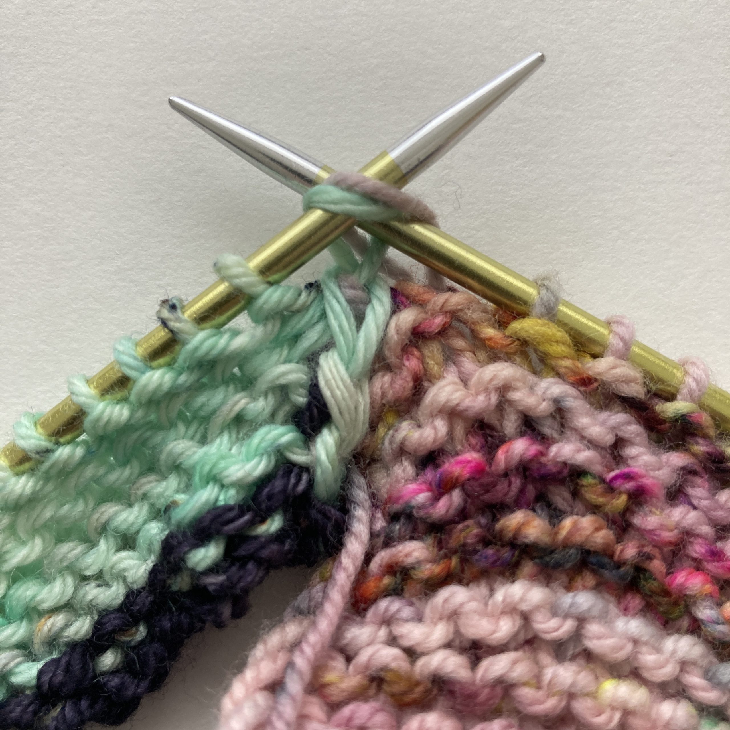 (WS) at start of row. K2TOG, joining live stitch from joining piece (pink) with working stitch (green) on the needle.